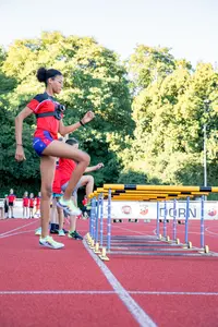 Eine Sportlerin der Turngemeinde Landshut trainiert im Freien auf der Laufbahn mit Hürden.