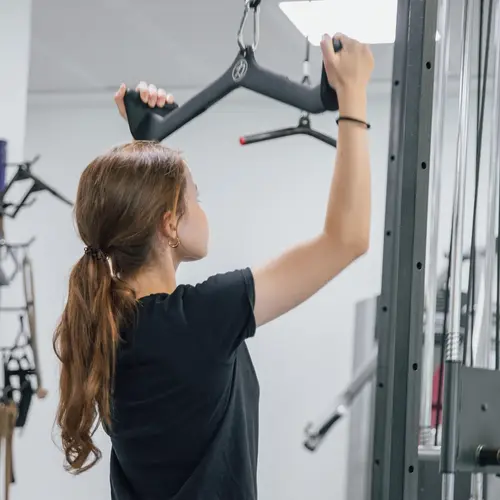Eine Frau trainiert im Fitnessstudio an einem Latzuggerät, das Teil des Sportangebots der Turngemeinde Landshut ist.