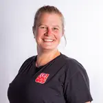 Eine lächelnde Frau im TGL-Shirt repräsentiert stolz den Sportverein der Turngemeinde Landshut.