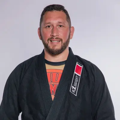 Ein Mann in einem schwarzen Gi mit lila Gürtel repräsentiert die Turngemeinde Landshut stolz im Kampfsport.