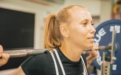 Eine Frau hebt konzentriert Gewichte im Fitnessstudio des Sportvereins Turngemeinde Landshut.