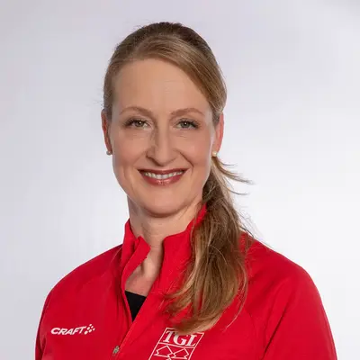 Eine Frau in roter TGL-Jacke lächelt, repräsentierend die Turngemeinde Landshut und ihren Sportverein.