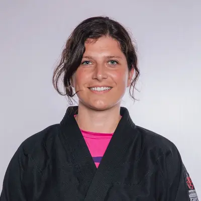 Eine Frau in einem schwarzen Kampfanzug lächelt und repräsentiert stolz den Sportverein TGL Landshut.