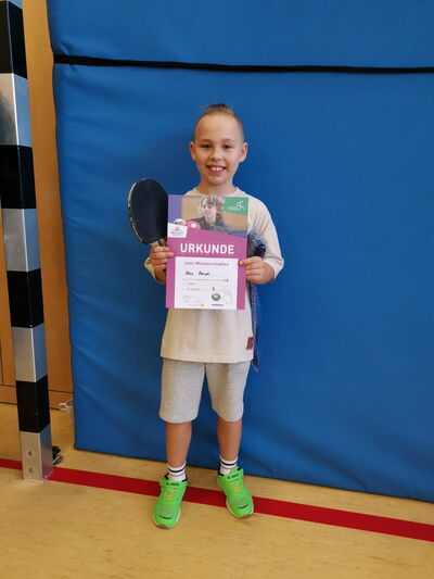 Ein Junge namens Alex hält stolz seine Urkunde im Sportverein Turngemeinde Landshut nach einem erfolgreichen Wettkampf.