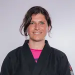 Eine Frau in einem schwarzen Kampfanzug lächelt und repräsentiert stolz den Sportverein TGL Landshut.