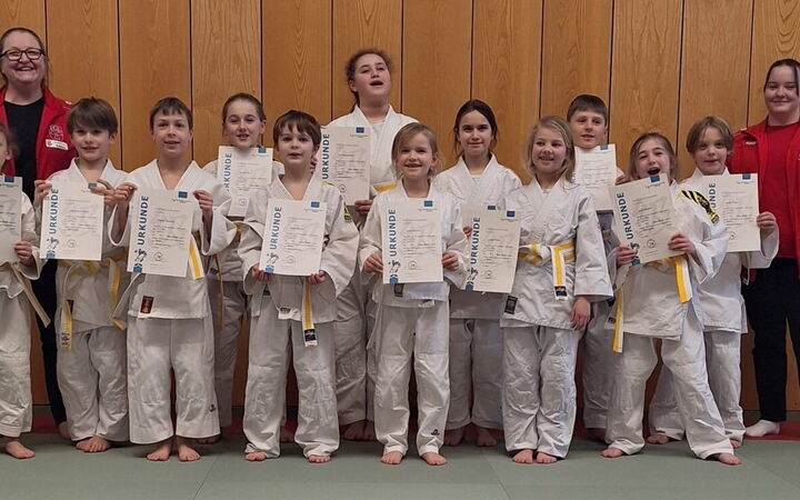 Eine Gruppe Schüler präsentiert stolz ihre Urkunden nach der Gürtelprüfung bei der Turngemeinde Landshut.