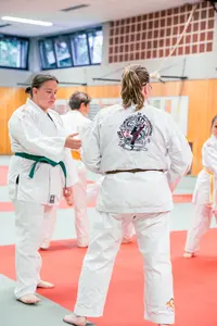 Teilnehmer in weißen Judoanzügen üben gemeinsam Techniken in einer Turnhalle des Sportvereins Landshut.