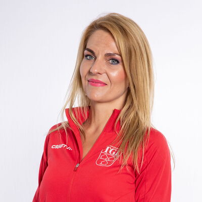 Eine lächelnde Frau trägt eine rote TGL-Jacke, symbolisierend den Sportgeist des Vereins Turngemeinde Landshut.