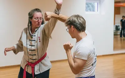 Zwei Personen üben Kampfsporttechniken in einem hellen Raum, als Teil des Landshut Vereins Turngemeinde.