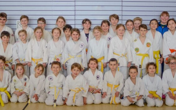 Eine Gruppe von Kindern in weißen Judoanzügen posiert für ein Mannschaftsfoto im Verein Turngemeinde Landshut.