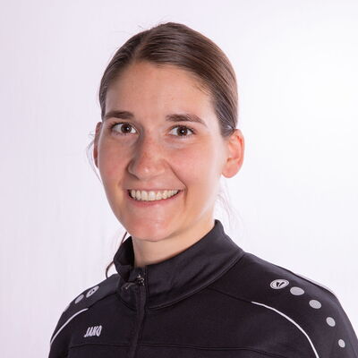 Eine lächelnde Frau in TGL-Sportkleidung repräsentiert stolz ihren Verein.