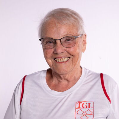 Eine Frau im TGL-Trainer-Shirt der Turngemeinde Landshut lächelt freundlich in die Kamera.