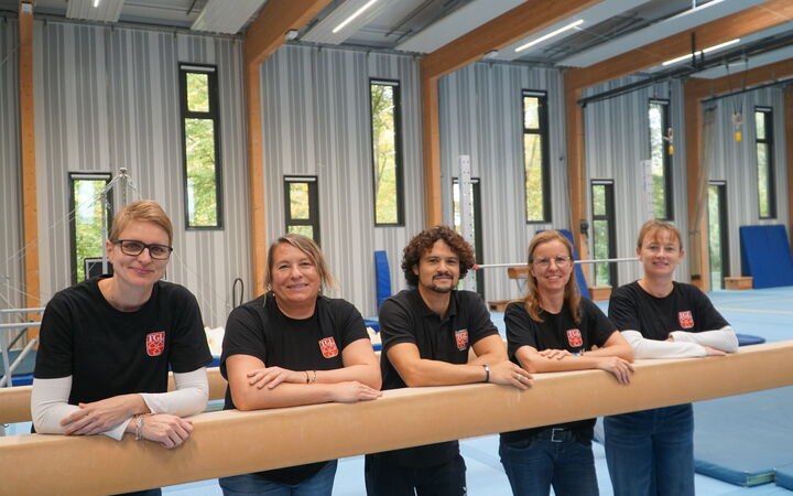 Fünf Übungsleiter in TGL-Shirts in der Turnhalle der TGL.