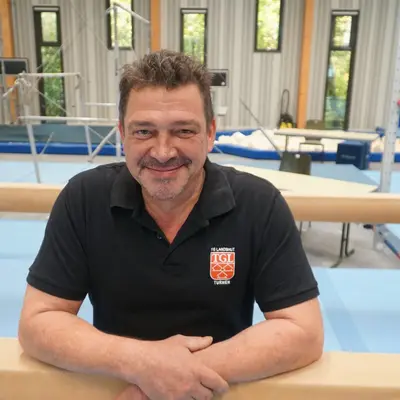 Ein Mann im blauen T-Shirt mit TGL-Logo repräsentiert stolz den Sportverein Turngemeinde Landshut.