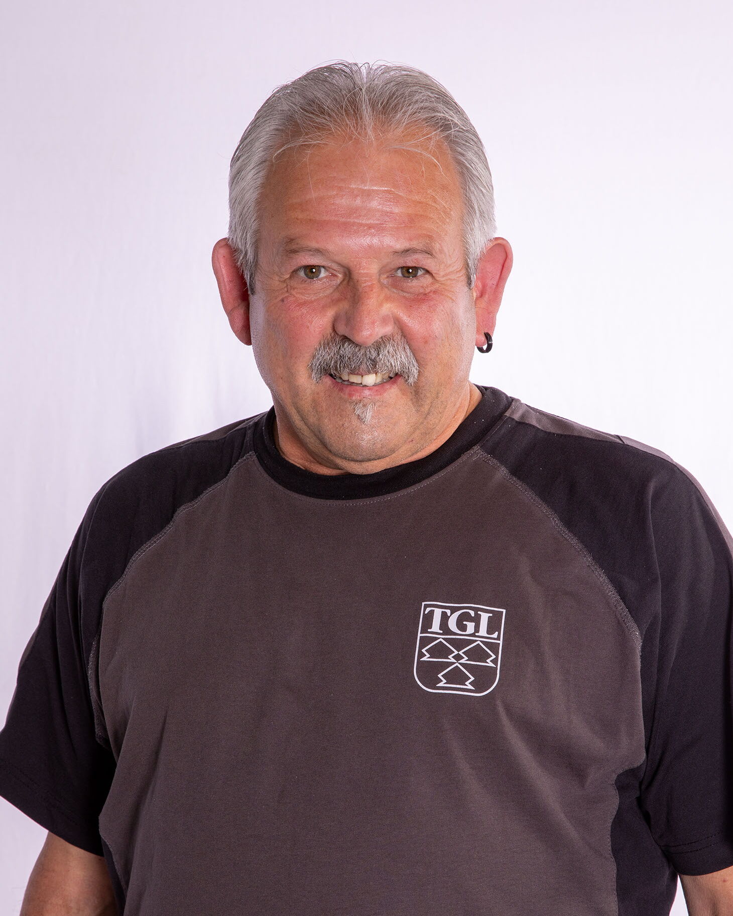 Ein lächelnder Mann in einem TGL-Shirt repräsentiert den Sportverein Turngemeinde in Landshut.