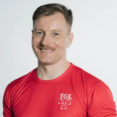 Ein lächelnder Mann trägt ein rotes TGL-Shirt mit Landshut-Skyline, das die Turngemeinde repräsentiert.