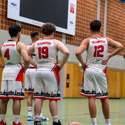 Basketballspieler des TG Landshut stehen in der Halle, bereit für das nächste Spiel des Vereins.