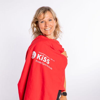Eine Frau in einem roten KiSS-Pullover lächelt und repräsentiert stolz den Sportverein Turngemeinde Landshut.