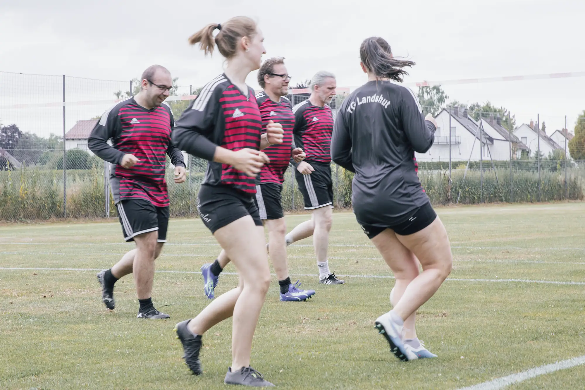 Eine Gruppe von Sportlern der Turngemeinde Landshut trainiert gemeinsam auf einem grünen Sportplatz.
