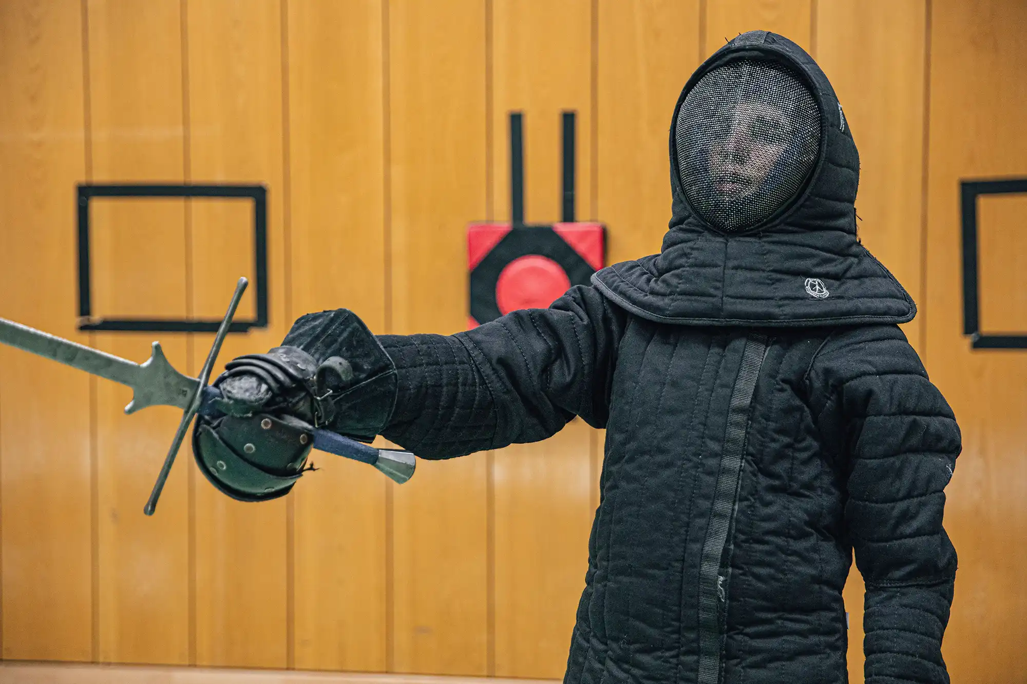 Ein Fechter in Schutzkleidung übt mit einem Schwert in der Turnhalle der Turngemeinde Landshut.