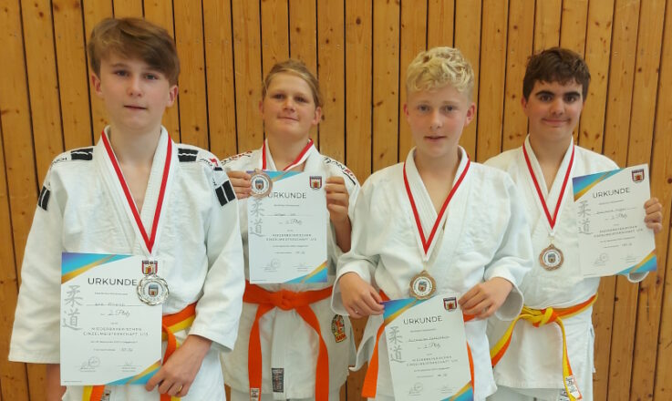 Vier junge Judoka der Turngemeinde Landshut zeigen stolz ihre Medaillen und Urkunden nach einem erfolgreichen Wettkampf.