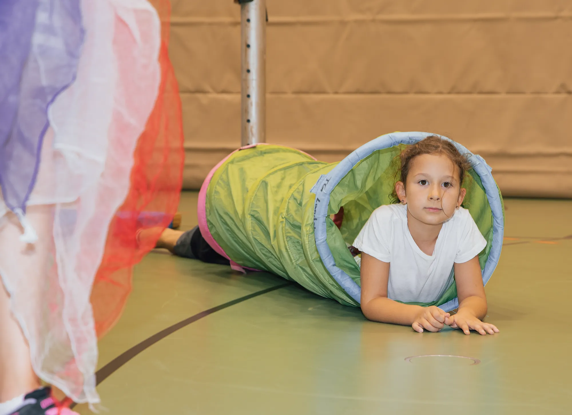 Ein Mädchen kriecht durch einen Tunnel bei einer Sportveranstaltung der Turngemeinde Landshut.