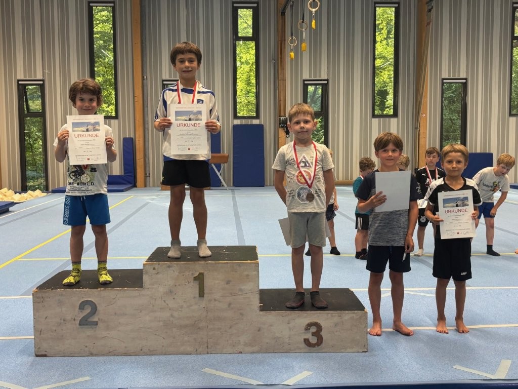 Junge Sportler der Turngemeinde Landshut präsentieren stolz ihre Urkunden und Medaillen bei einem Wettkampf im Verein.